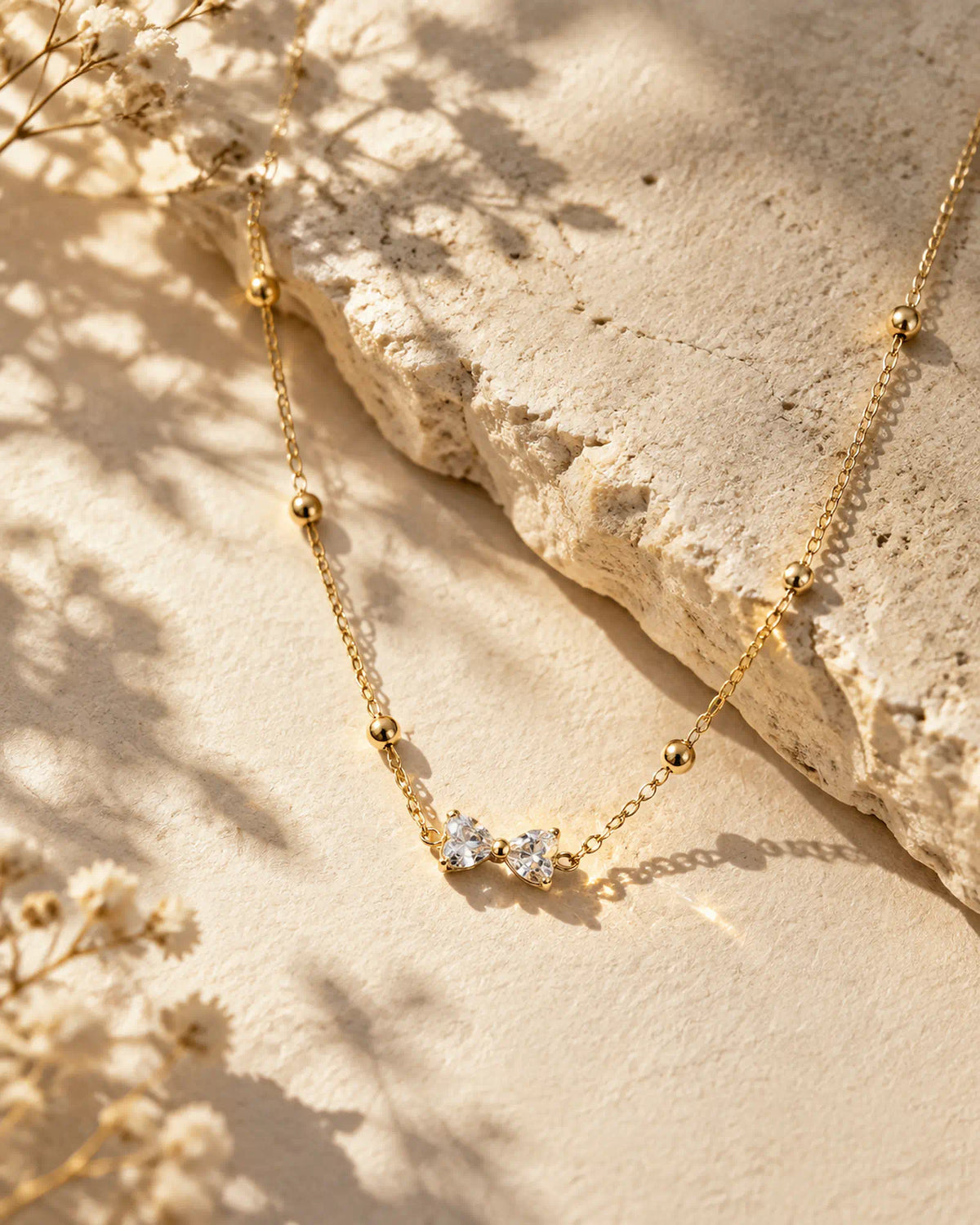 Wearlumi Beaded Bow Pendant Necklace on warm limestone textured background
