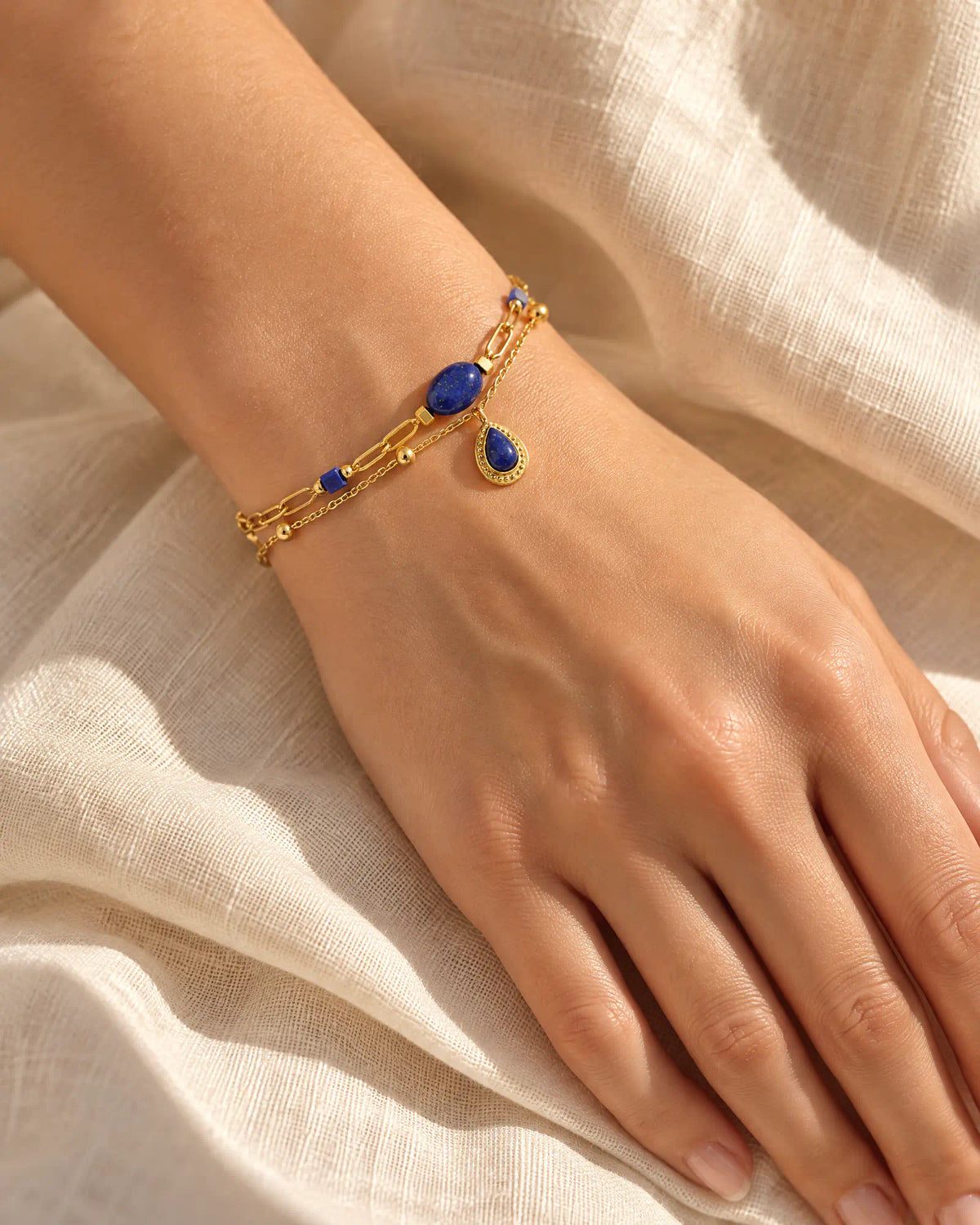 Hand resting relaxed on table wearing Midnight Teardrop Layered Bracelet