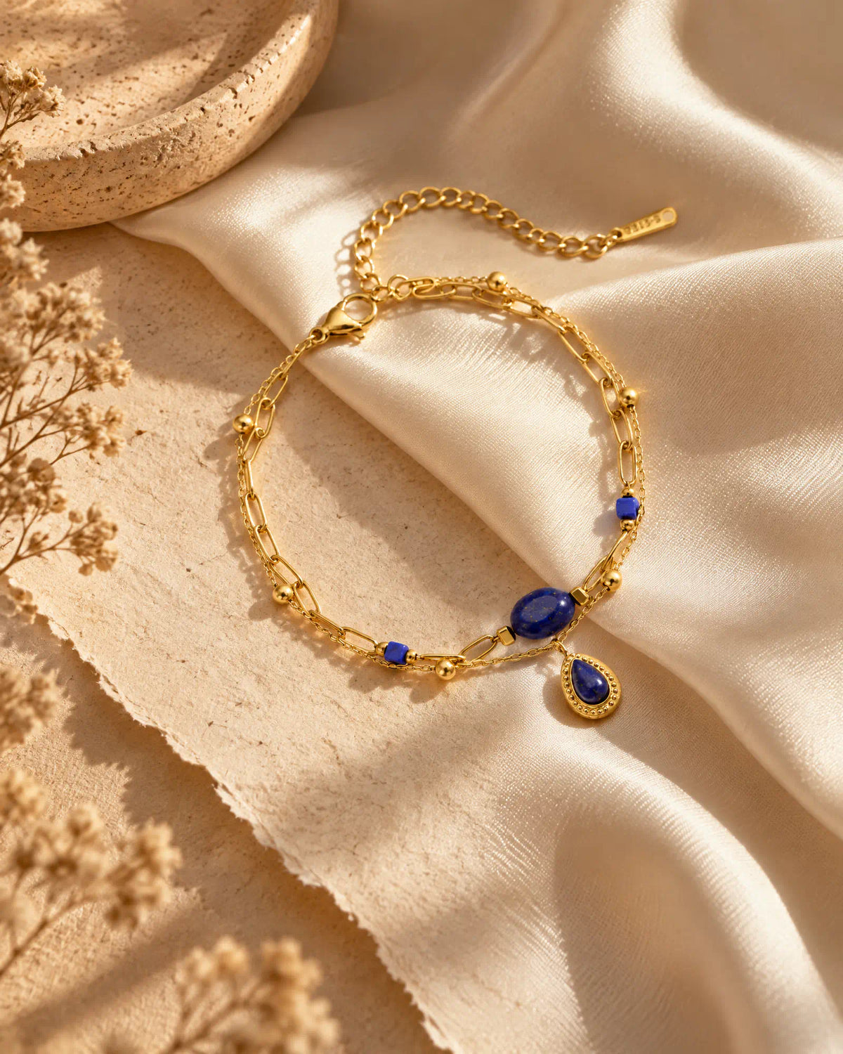 Midnight Teardrop Layered Bracelet draped over smooth silk fabric