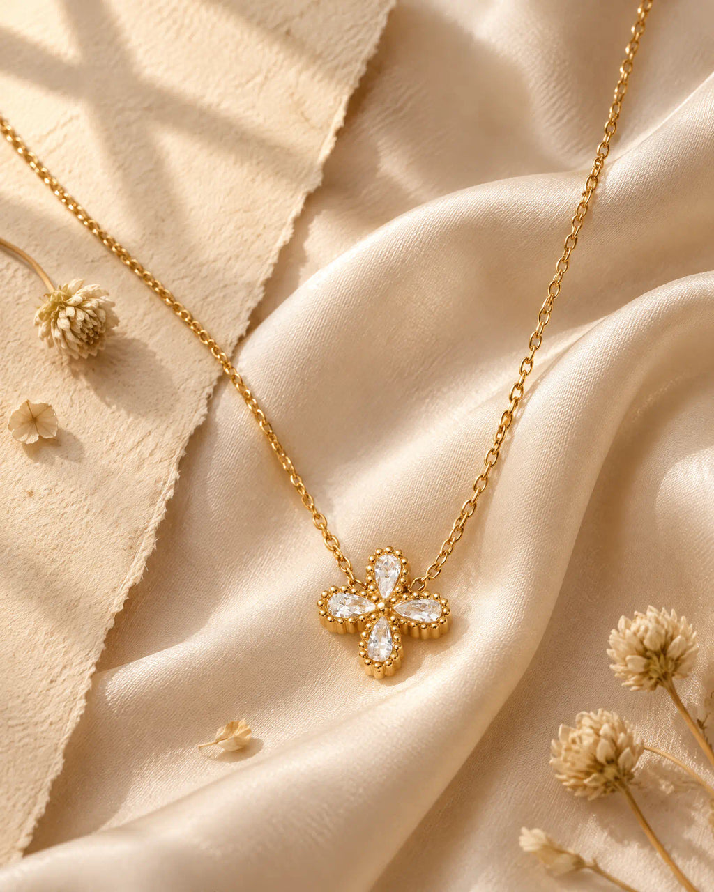 Wearlumi Four Petal Beaded Clover Pendant Necklace draped over champagne silk fabric