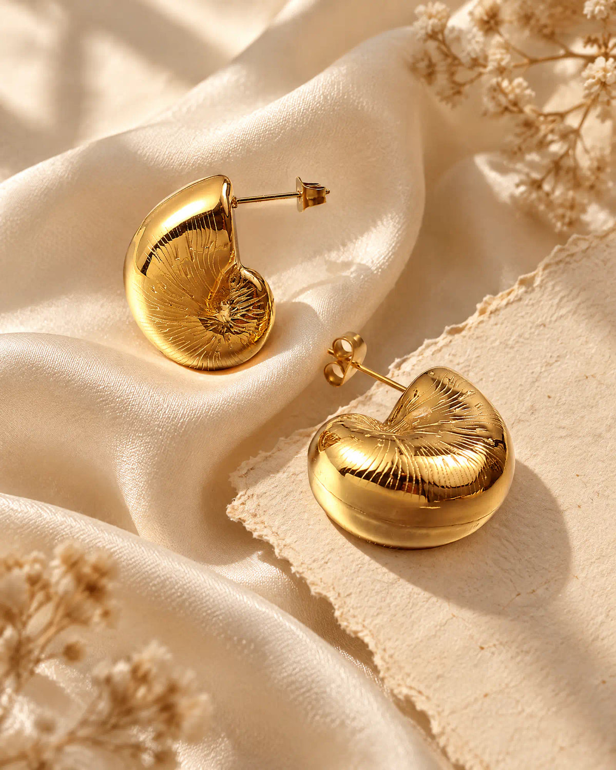 Coiled Nautilus Shell Studs flat lay on champagne silk fabric
