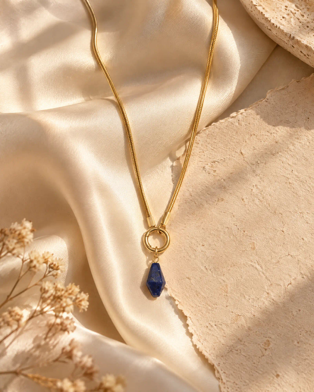 Midnight Faceted Prism Pendant draped across champagne silk fabric