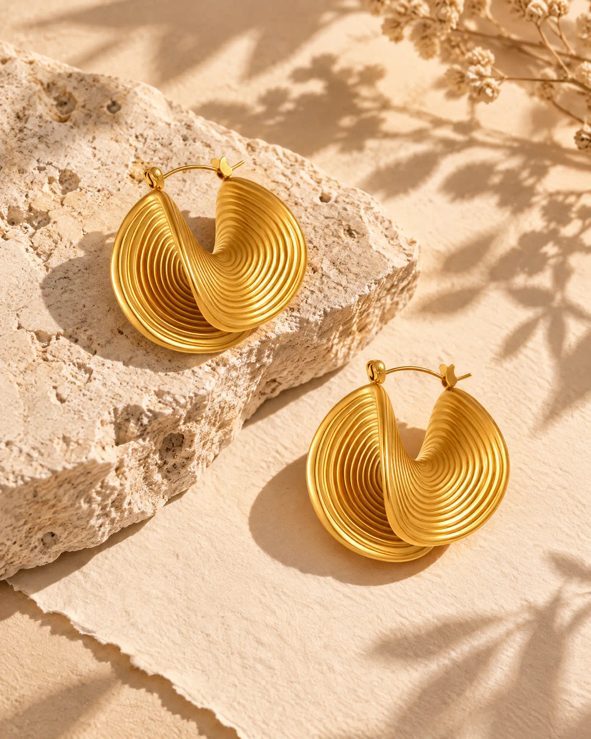 Pair of Spiral Twist Statement Earrings resting on limestone stone