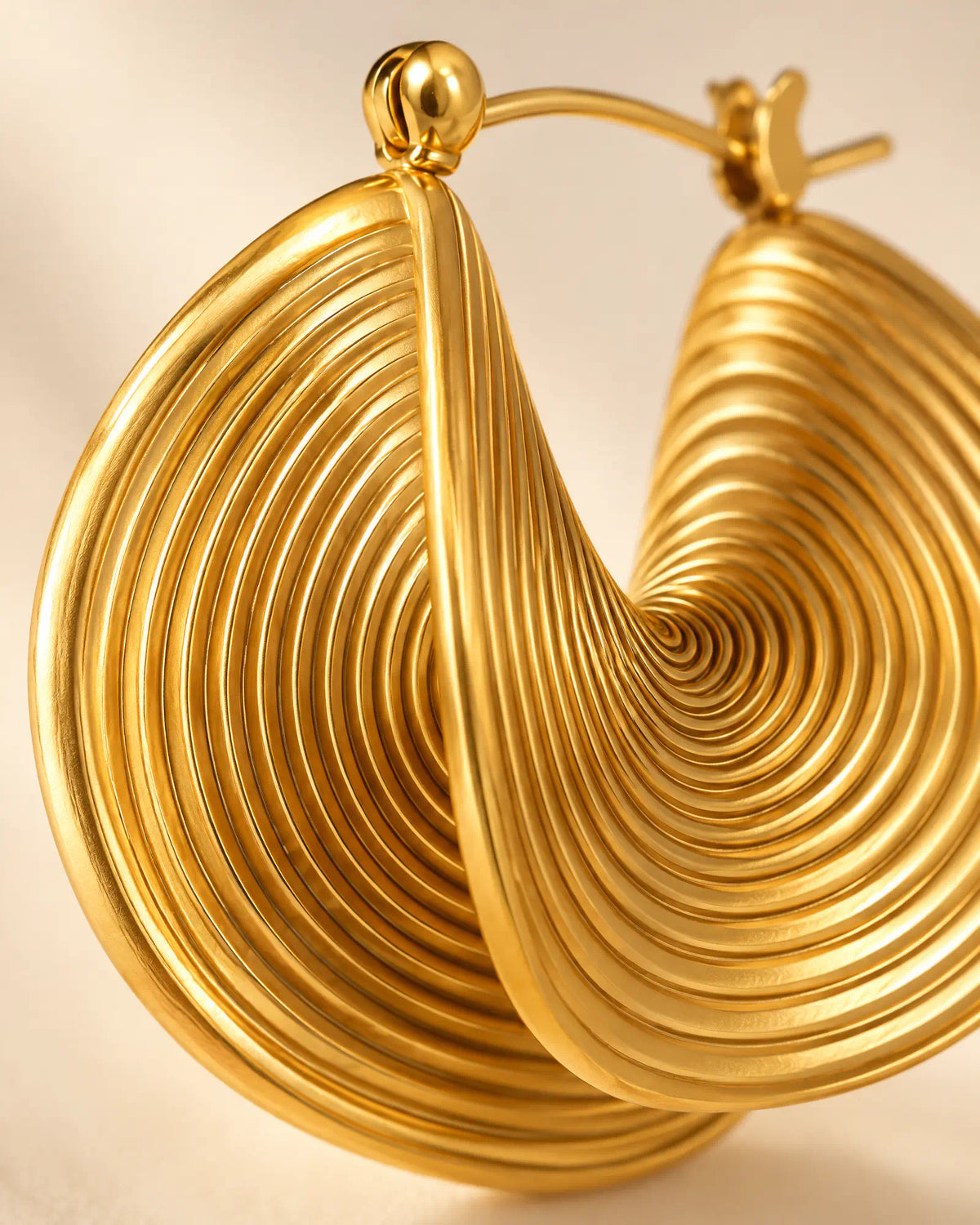 Macro detail of concentric grooved ridges and hinge closure on Spiral Twist Statement Earrings