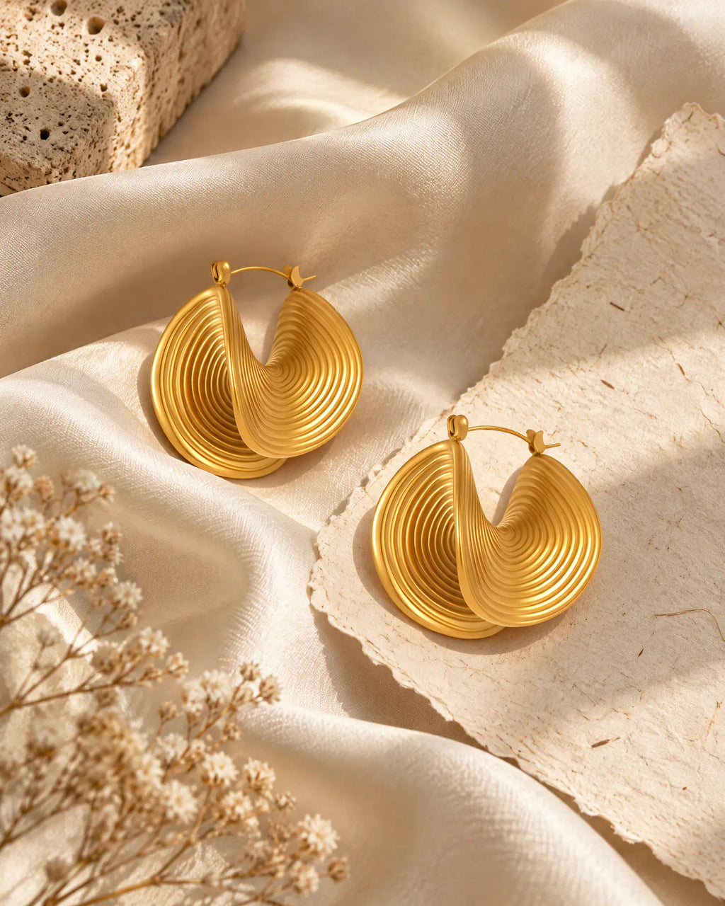 Spiral Twist Statement Earrings draped on smooth silk fabric