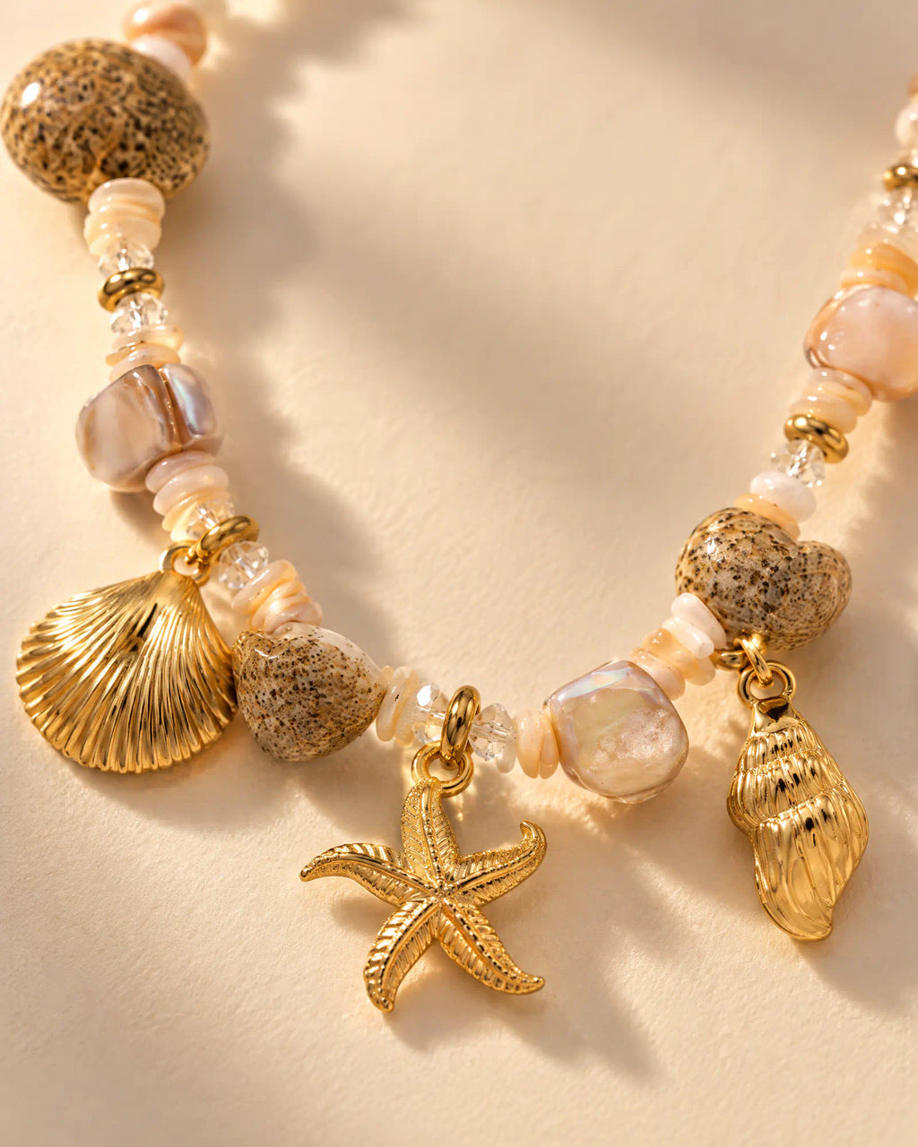 Close-up macro detail of starfish charm, shell pendants, and textured beads