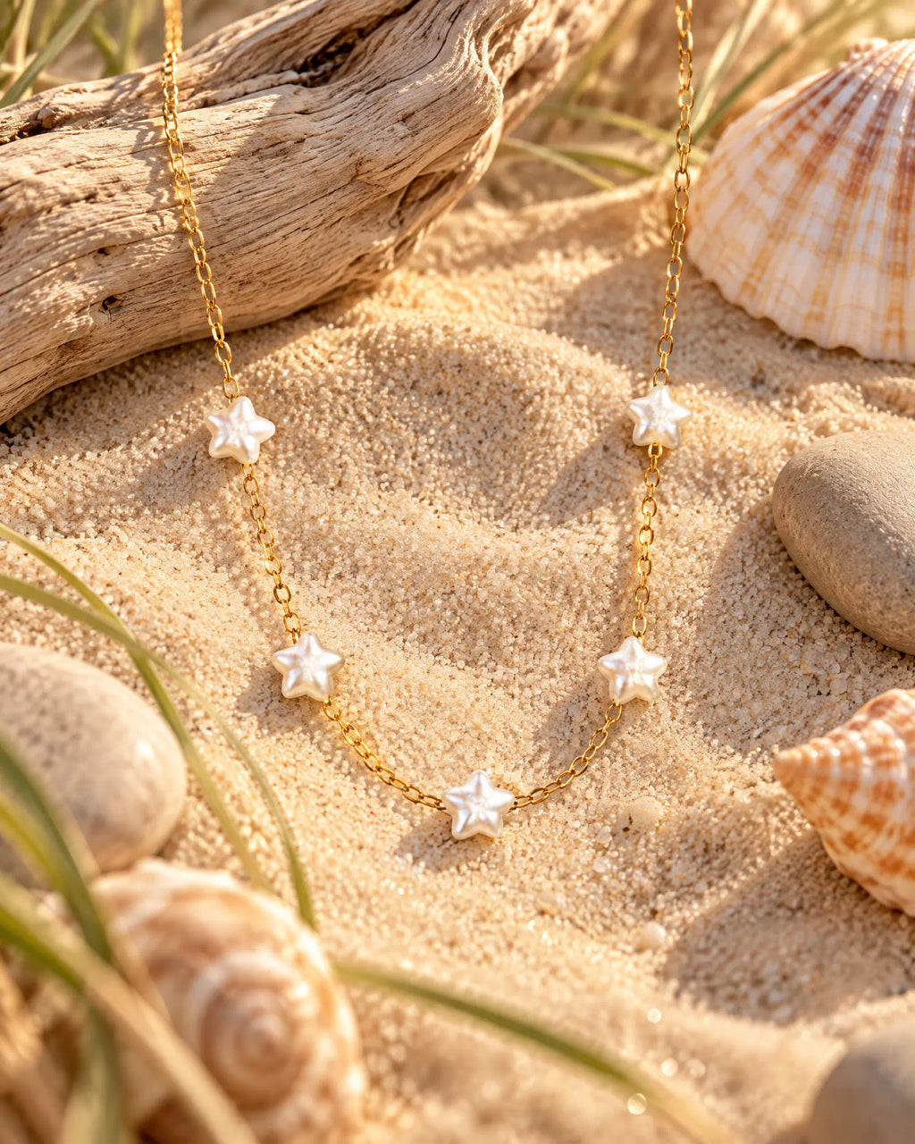 Starlight Station Necklace resting on sand beside driftwood and shells