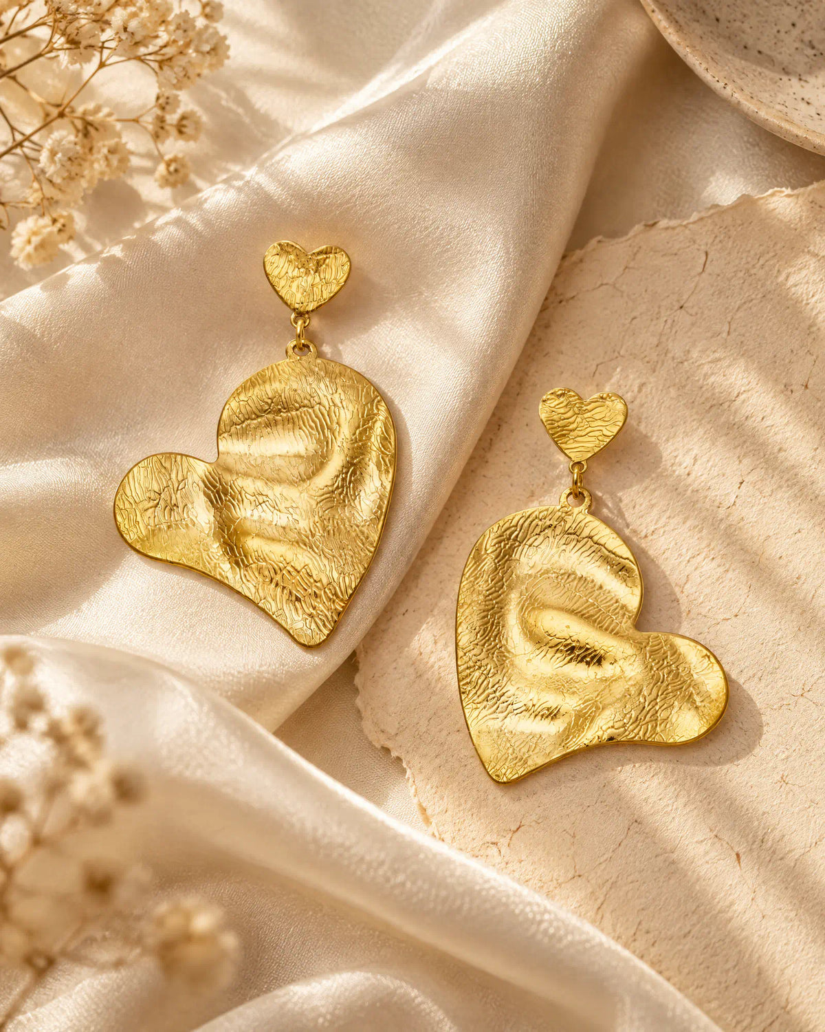 Rippled heart drop earrings on draped silk cloth