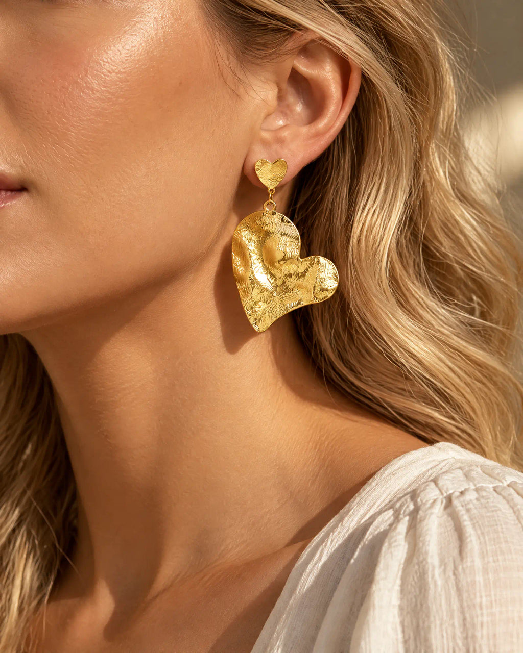Rippled heart drop earring three-quarter angle worn on model