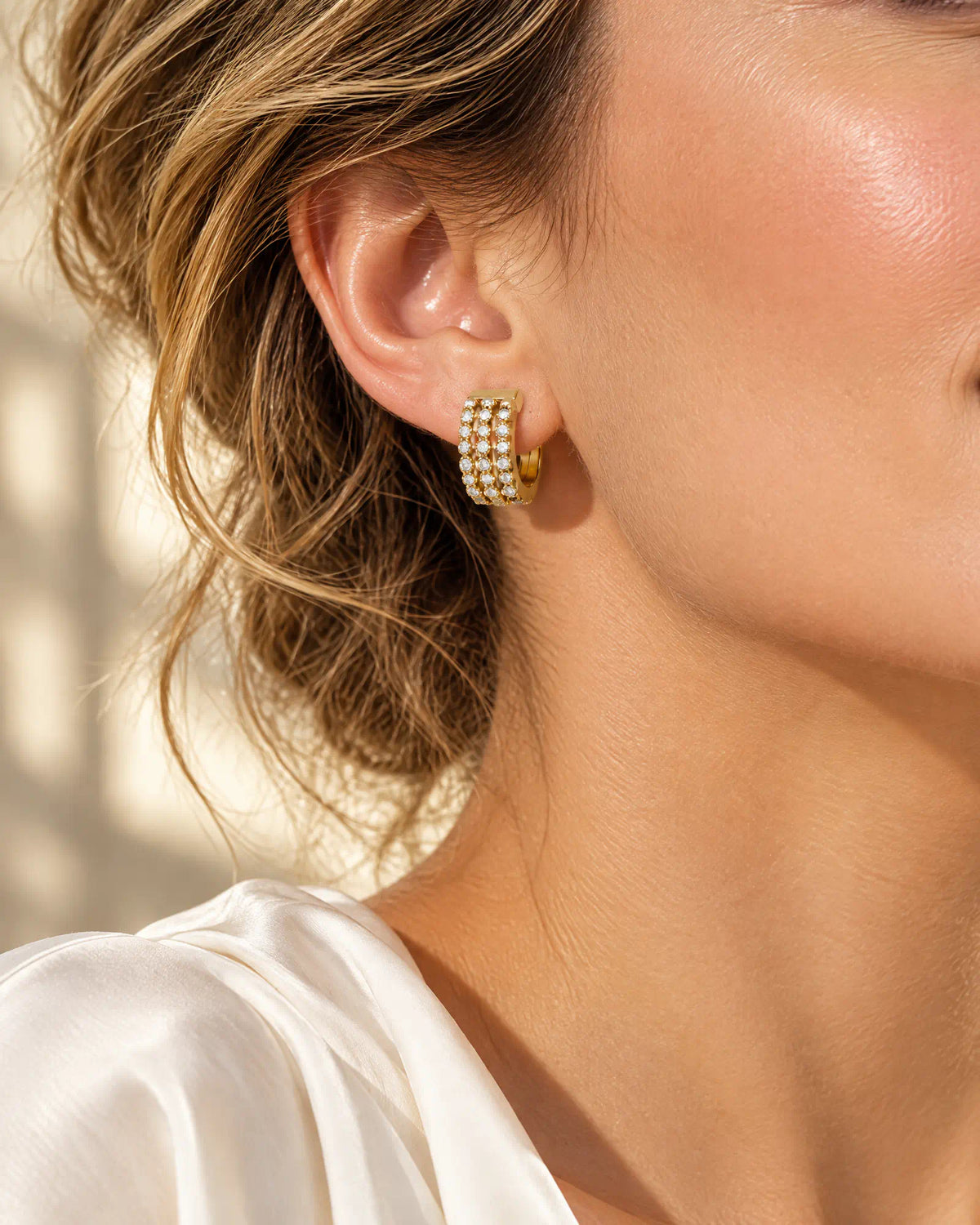 Three-quarter view of model wearing triple row huggie hoop earring